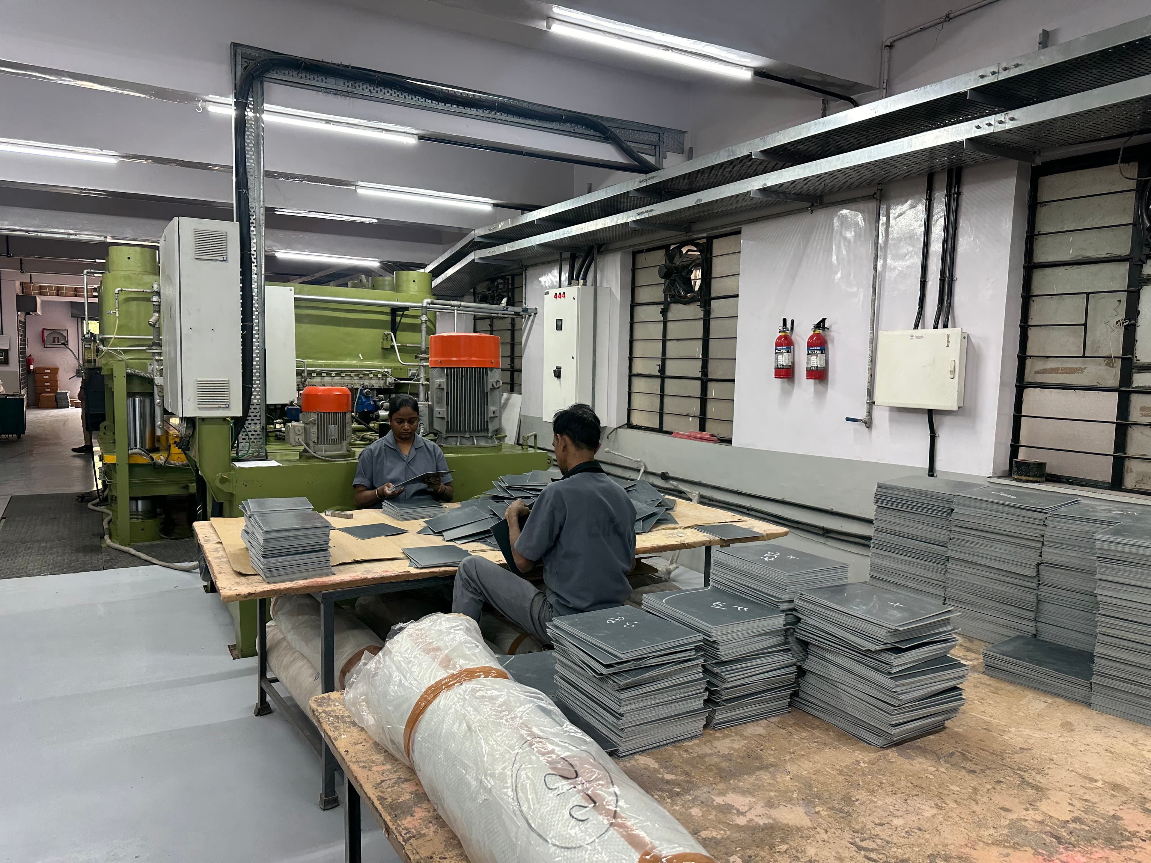 Team members inspecting and sorting finished FRP sheets on the production floor
